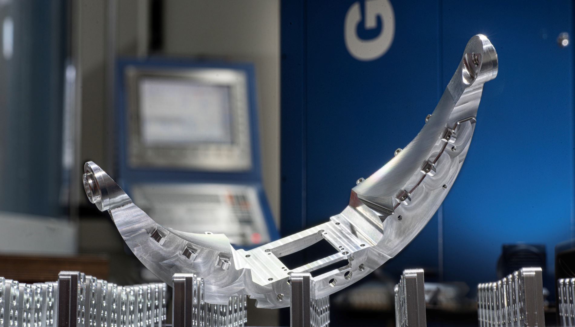 Large curved machined aluminum structural part beside CNC machine