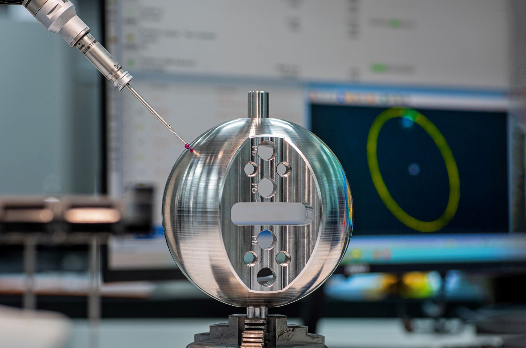 CMM probe scanning a round part beside measurement display