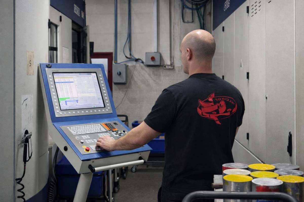 Machinist operating a CNC control panel on the floor